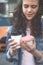 Hands holding a donut and coffee on the background of a busy metropolis