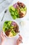 Hands holding and eating from a Waldorf salad bowl with another matching salad above.