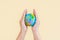 Hands are holding the globe with yellow background. The concept of saving the world and caring for the world