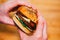Hands holding gourmet double Bacon Cheese Burger