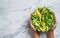 Hands holding healthy fresh summer salad with avocado, kiwi, apple, cucumber, pear, greens and sesame with smoothie on light