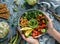 Hands holding healthy superbowl or Buddha bowl with salad, baked sweet potatoes, chickpeas, broccoli, hummus, avocado, sprouts on