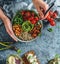 Hands holding healthy superbowl or Buddha bowl with salad, sweet potatoes, chickpeas, quinoa, tomatoes, arugula, avocado on light