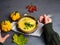 Hands holding hot cream homemade sweet potato and pumpkin soup on the grey table, top view