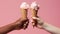 Hands holding icecream cones on pink background