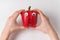 Hands holding large red pepper with funny scared face. Pepper with Googly eyes on white background