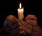 Hands holding lighted candle in darkness