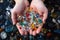 Hands holding microplastics picked up on a beach. Water pollution, ecology, environmental pollution