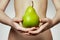 Hands holding pear. Portrait of young woman holding pear in her