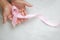 Hands holding pink ribbon curl on white isolated fabric with copy space. Breast cancer Awareness, male breast cancer disease,