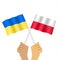 Hands holding Polish  flag and ukrainian flag.