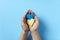 Hands holding and protecting blue and yellow paper hearts; support for Ukraine