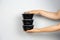 hands holding ready meal in black containers against gray wall, delivery concept