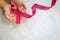 Hands holding Red burgundy ribbon bow on white fabric background with copy space, symbol of Multiple Myeloma or Plasma cell cancer