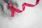 Hands holding Red burgundy ribbon bow on white fabric background with copy space, symbol of Multiple Myeloma or Plasma cell cancer