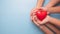 Hands holding a red heart on blue background, CSR or Corporate Social Responsibility