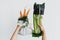Hands holding reusable eco friendly bag with fresh carrots against celery in cellophane plastic package on white background. Zero