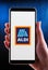 Hands holding smartphone displaying logo of Aldi