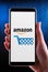Hands holding smartphone displaying logo of Amazon