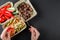 Hands holding sport nutrition with pasta, fried liver and fresh vegetables in plate on black background. Healthy food, dieting,