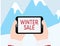 Hands holding tablet with WINTER SALE text on Blue mountains with snow background