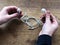 Hands holding tangled headphones across wooden table close-up. Technology