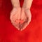 Hands holding two red hearts with word love on red background. St. Valentines Day concept. Square.