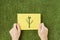 Hands are holding a yellow sheet of paper with an ecological symbol on it