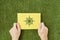 Hands are holding a yellow sheet of paper with an ecological symbol on it