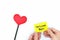 Hands holding a yellow welcome back note card with a red heart. Back to work, office and school concept.