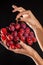 Hands holdings a bunch of red grapes in studio with black background