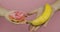 Hands holds donut and banana. Choice donut against banana. Healthy or junk food