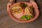 Hands of human hold plate of fresh appetizing sandwich on table background closeup, top view. Serving of sliced meat