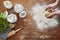 Hands kneading pasta dough flour and kitchen utilities on wooden workspace