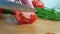 Hands knife cut tomato on a wooden board slow-motion shot