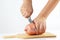 Hands with a knife sliced sausage on a cutting board closeup