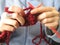 Hands knitting a magenta scarf