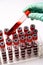 Hands of a lab technician with a test tube of blood sample and a rack with other samples over light grey background