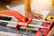 Hands of laborer using cutting tile machine at construction site with sun flare background