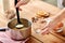 Hands with ladle pouring eggnog from pot to glass