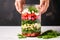 hands layering fresh watermelon and crumbled feta in a mason jar salad