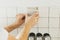 Hands laying modern square tile on adhesive close up. Worker installing stylish white tiles on plaster wall. Renovation