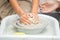 Hands of a little girl who sculpts a craft on a potter\'s wheel