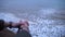 Hands of lone young man sitting on the edge of cliff above dirty sea water