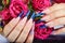 Hands with long artificial blue french manicured nails and rose flowers