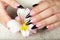 Hands with long artificial french manicured nails holding a lily flower