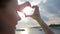 Hands made heart shape at sunset on sea in summer, beautiful woman making love symbol