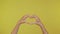 Hands make love sign. Hands silhouette making a love sign over a yellow background 4K