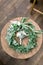 Hands making wedding wreath from eucalypthus and flowers and groom boutonniere from white flowers and greenery on wooden