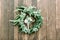 Hands making wedding wreath from eucalypthus and flowers and groom boutonniere from white flowers and greenery on wooden